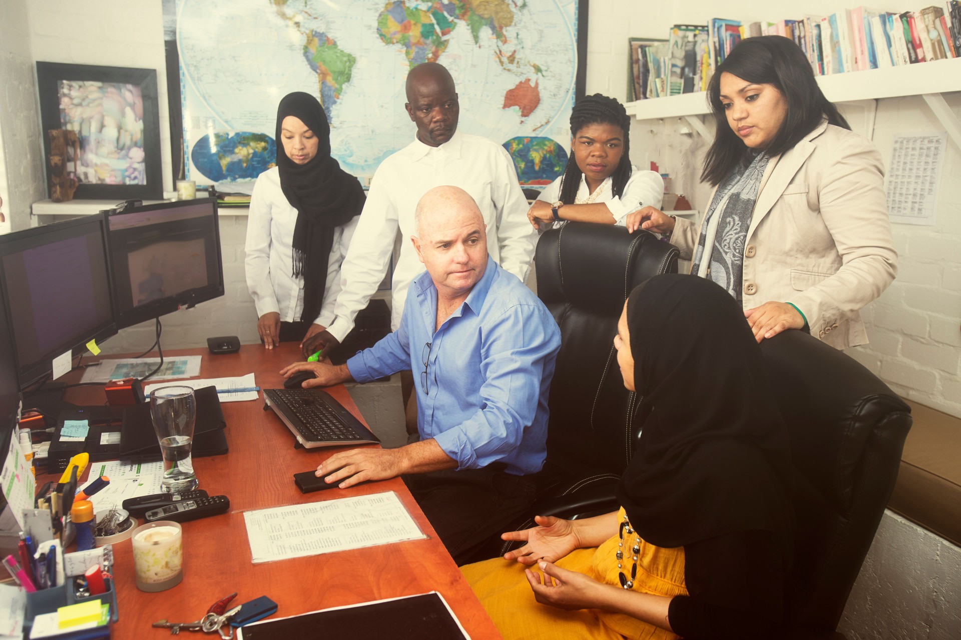 Corporate team leader strategizing with co-workers in the office looking at the computer monitior